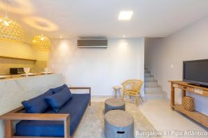 a living room with a blue couch and a tv at Pipa Atlântico Bungalow 41 in Pipa