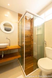 a bathroom with a glass shower and a toilet at Pipa Atlântico Bungalow 41 in Pipa