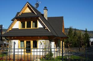 ein Haus mit einem schwarzen Dach und einem Zaun in der Unterkunft domek nad potokiem in Kościelisko