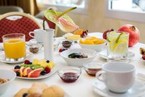 a table with a breakfast of fruit and juice at Hotel De Londres in Rimini