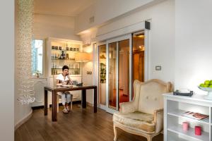 a person sitting at a table with a laptop at Hotel De Londres in Rimini