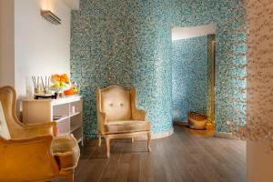 a living room with a chair and a wall covered in wallpaper at Hotel De Londres in Rimini