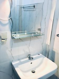 a white bathroom with a sink and a mirror at Vivid Lanka in Bentota