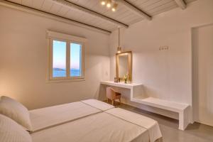 um quarto branco com uma cama e uma janela em White Cliff Naousa em Naousa