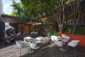 a patio with white chairs and tables and a tree at Morada la Noria in El Gallinero