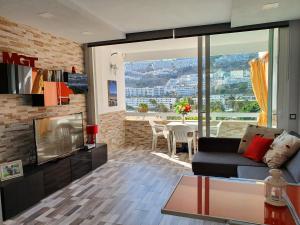 een woonkamer met een bank en een open haard bij MGT - Appartamento sulla Spiaggia con terrazza romantica in Puerto Rico de Gran Canaria