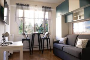 een woonkamer met een bank, een tafel en een raam bij STUDIO PROMENADES DES ANGLAIS - CARRE&OR NICE in Nice