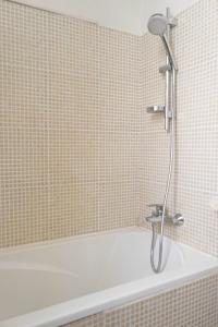 een wit bad met een douche in de badkamer bij STUDIO PROMENADES DES ANGLAIS - CARRE&OR NICE in Nice