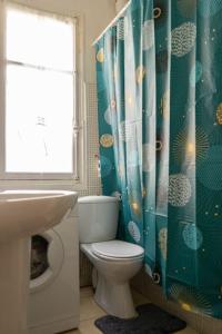 a bathroom with a toilet and a blue shower curtain at STUDIO PROMENADES DES ANGLAIS - CARRE&OR NICE in Nice