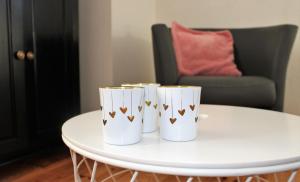 ザントフォールトにあるAppartement Kwaakの白いテーブルと椅子の上に置かれた白いカップ2つ