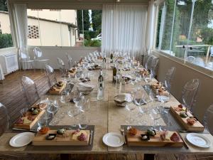 un lungo tavolo con piatti di bicchieri da cibo e da vino di Villa I Barronci Resort & Spa a San Casciano in Val di Pesa