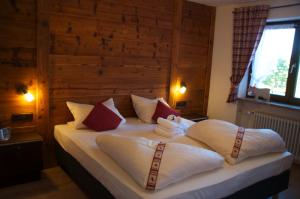 a bedroom with a bed with white sheets and red pillows at Bergbauernwirt im Landhaus Bolgental in Bolsterlang