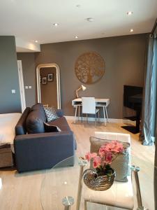 uma sala de estar com um sofá e uma mesa com flores em NEW - Kings Wharf Quay29 - Large Studio Apartment with 3 Pools - Gym - Rock Views - Holiday and Short Let Apartments in Gibraltar em Gibraltar