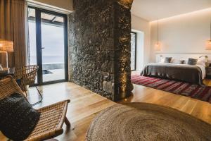 a bedroom with a bed and a stone wall at SENSI Azores Nature and SPA in Ginetes