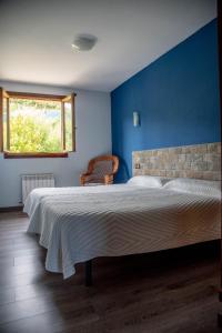 a bedroom with a large bed with a blue wall at Gure ametsa in Getaria