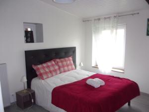 1 dormitorio con 1 cama con manta roja y ventana en cheztitoine, en Pouzauges