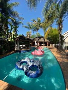 uma grande piscina com um rio lento com dois insufláveis em Summerview Guest Lodge em Joanesburgo