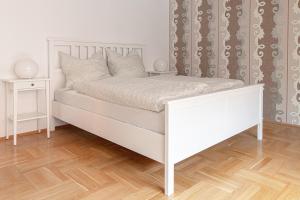 Schlafzimmer mit einem weißen Bett und Holzboden in der Unterkunft Ferienwohnungen Bockstraße in Quedlinburg