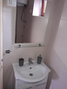 La salle de bains blanche est pourvue d'un lavabo et d'un miroir. dans l'établissement Apartment By The Sea Marko, à Banj