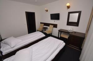 a hotel room with two beds and a desk and a mirror at Hotel Cerbul in Statiunea Borsa