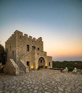 un gran edificio de piedra con una puesta de sol en el fondo en Cassiopeia's Castle, en Gythio