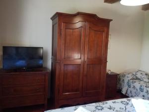 una camera da letto con un grande armadio in legno e una TV di Badia il Vingone a Città di Castello