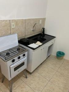 a kitchen with a stove and a sink at Apartamento beira da Praia das Ondinas in São Lourenço do Sul