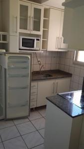 cocina con armarios blancos, fregadero y microondas en Apartamento Ecologic Park, en Caldas Novas