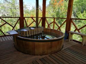 uma banheira de madeira num alpendre com um banco em Parque Amavida em Malalcahuello