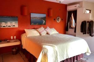 a bedroom with a bed with an orange wall at Newer & Roomy w/2 Pools. No Car Needed. Beaches, Restaurants & Shopping W/I walking distance. Taxis and buses abundant for reasonable price if needed in Zihuatanejo