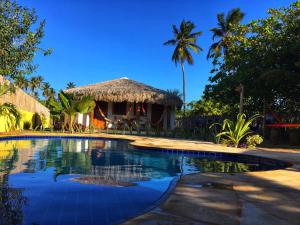 a resort with a swimming pool and a hut at Pousada Icaraizinho Praia in Icaraí