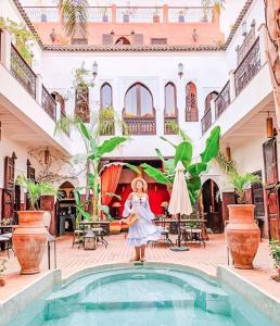 Una donna in piedi di fronte a una piscina in una casa di Riad Pachavana a Marrakech
