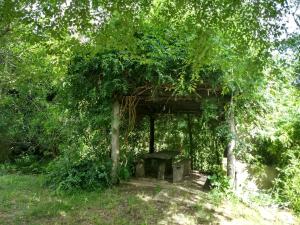 un cobertizo con un banco bajo un árbol en Casa grande con jardin en Ostende
