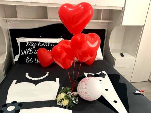 a bed with red balloons and a bunch of hearts at Pandora Luxury Suite in Carovigno