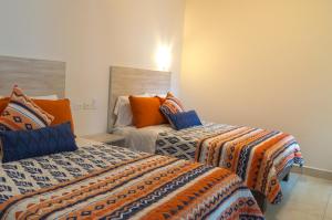 Nuevo Casas GrandesにあるMagnolias Suites Hotelのオレンジとブルーの部屋のベッド2台