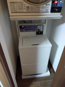 a washer and dryer in a corner of a room at Nice Hostel Yahiro in Tokyo