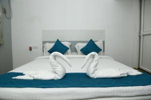 una cama con dos cisnes hechos de toallas en The Base Inn (where convenience meets luxury), en Pondicherry