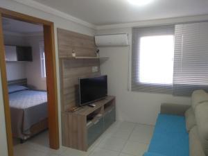 a small living room with a television and a bed at Apto Aconchego da Serra - Bairro Maria Goretti in Bento Gonçalves