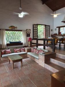 a living room with couches and a table and windows at Casa pé na areia em Toque Toque in São Sebastião