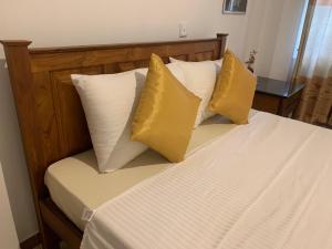 ein Bett mit vier gelben Kissen darauf in der Unterkunft White House - Orange Hill Avenue in Ragama