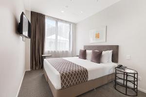 um quarto de hotel com uma cama e uma televisão em Ramada Suites Victoria Street West em Auckland