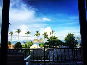 a view of palm trees and the ocean from a balcony at Thanya Beach Resort - SHA Plus in Ko Ngai