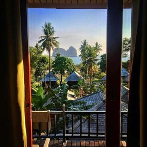 a room with a view of the ocean and palm trees at Thanya Beach Resort - SHA Plus in Ko Ngai