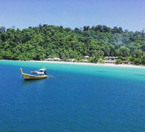 a boat in the middle of a body of water at Thanya Beach Resort - SHA Plus in Ko Ngai