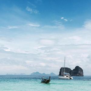 a boat in the ocean with two boats in the water at Thanya Beach Resort - SHA Plus in Ko Ngai