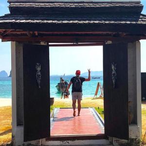 a man walking on a wooden boardwalk near the ocean at Thanya Beach Resort - SHA Plus in Ko Ngai