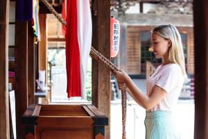 a young girl is holding onto a rope at 宿坊 観音院 Temple Hotel Kannonin in Kiryu