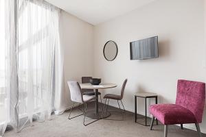 a room with a table and chairs and a tv at Ramada Suites Victoria Street West in Auckland