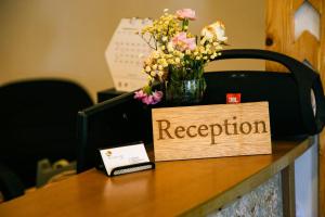 un cartel de reserva en un escritorio con flores. en Beach Grand & Spa Premium, en Hulhumale