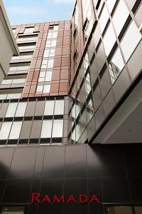 een uitzicht op een hoog gebouw met een rood rambadi-bord bij Ramada Suites Victoria Street West in Auckland
